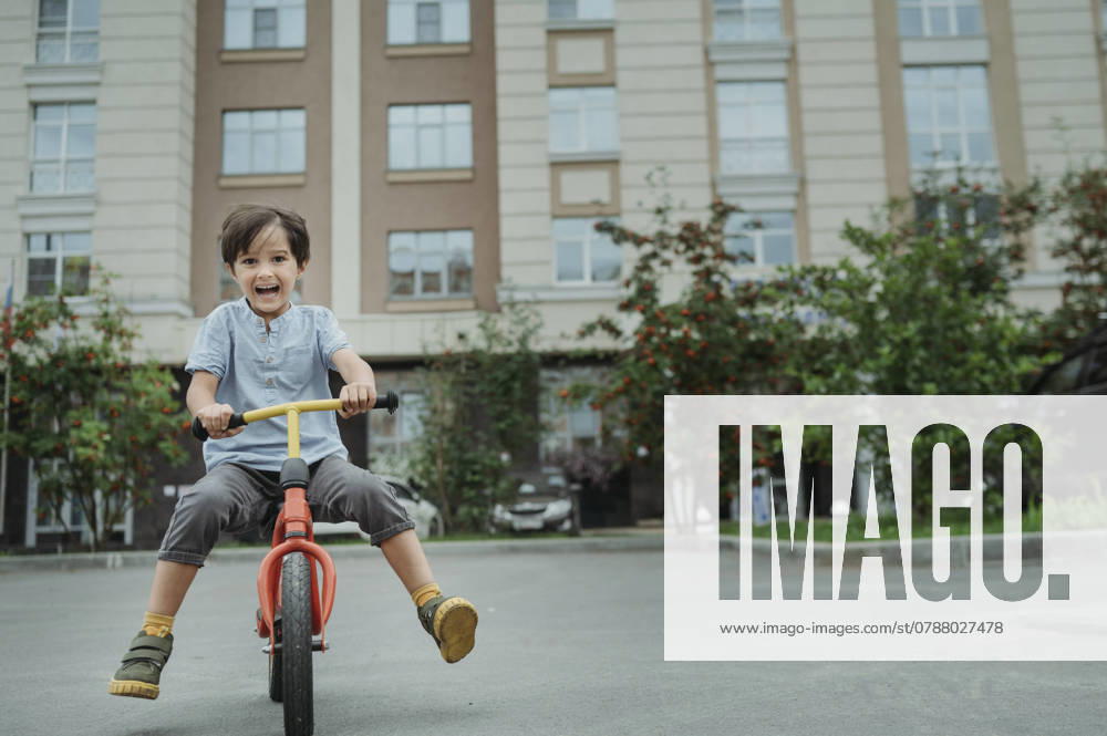 Happy boy riding bicycle in front of building model released, Symbolfoto, ANAF04287