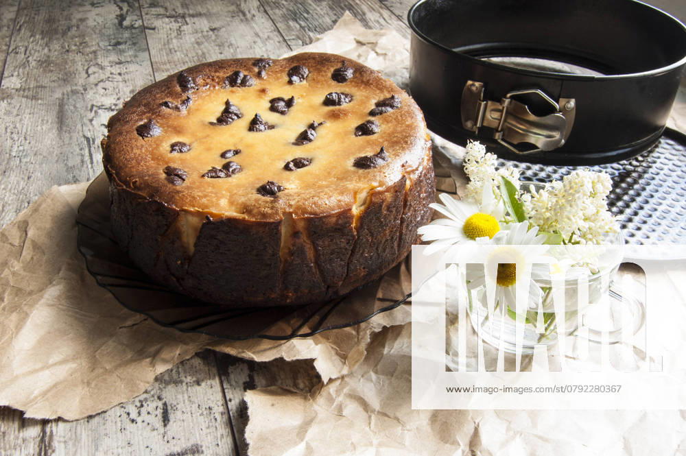 Cheesecake on an old table with a bouquet of daisies and a form for baking. Near wrapping paper. Retro style. From the series Still Life with cheesecake , 46003260.jpg, celebrations, dessert, chocolate, food, sweet, flower, cake, cheesecake, cheese, baking, decoration, table, gourmet, single, eating, plate, temptation, brown, traditional, biscuit, easter, cherry, refreshment, pastry, white, dishware, homemade, close-up, colors, cream, freshness, portion, tablecloth, nobody, yellow, life, breakfast, spoon, wood, part, amomile, glass cup, bouquet, packaging paper, still life, retro, horizontal RECORD DATE NOT STATED