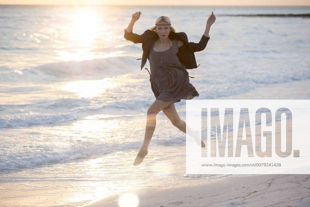 Young woman jumping for joy on the beach model released Symbolfoto ZOCF00420