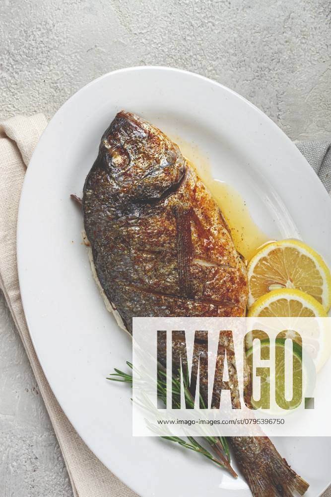 Gebackene Goldbrasse, im Ofen, gebratene Goldbrasse, mit Gewürzen und Kräutern, auf einem weißen Teller, von oben, hausgemacht, ohne Personen Baked dorado fish, in the oven, fried dorado, with spices and herbs, on a white plate, top view, homemade, no people
