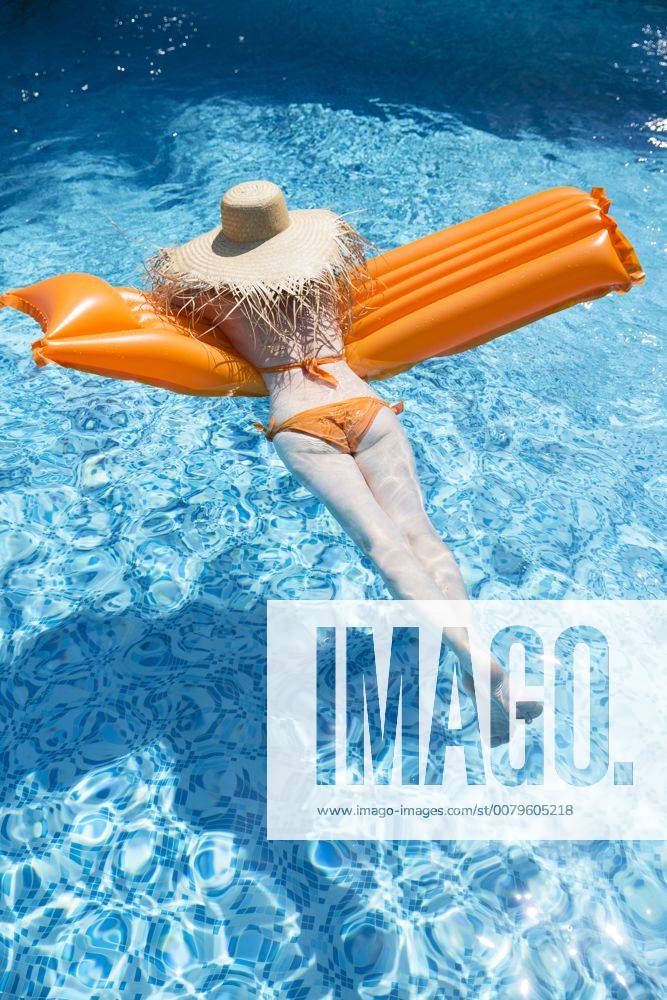 Back view of woman relaxing on orange airbed in swimming pool model released Symbolfoto property released MAEF12350