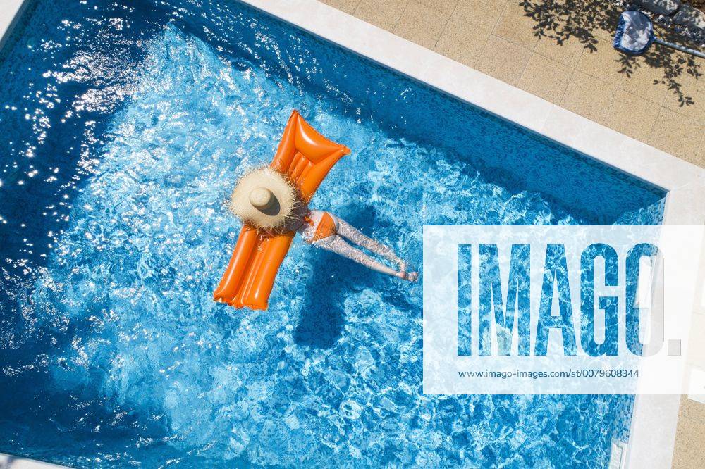 Back view of woman relaxing on orange airbed in swimming pool model released Symbolfoto property released MAEF12347