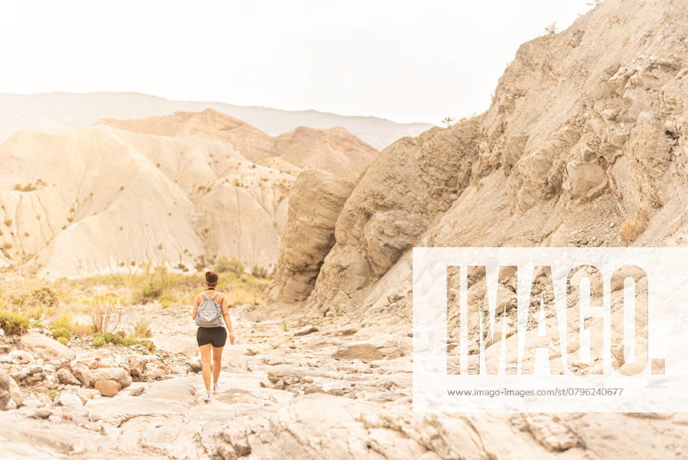 Back view of anonymous female tourist with backpack exploring sandy mountainous terrain in Tabernas desert, model released, , 48349154.jpg, woman, traveler, tourist, desert, adventure, wanderlust, hike, vacation, trekking, nature, mountain, archaeologist, explorer, female, arid, dry, valley, lady, walk, journey, trip, tabernas, backpack, terrain, explore, spain, tourism, landscape, travel, scenic, almeria, waterless, discovery, ridge, summer, activity, formation, sky, range, cloudless, daytime, sunlight, alone, outdoors, copy space, anonymous, unrecognizable, back view RECORD DATE NOT STATED