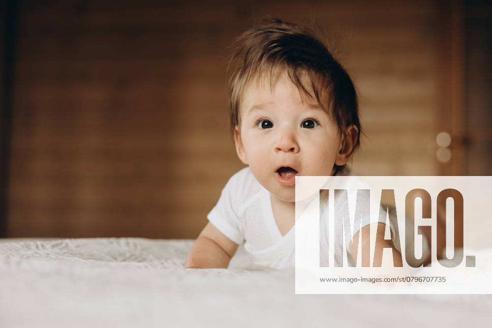 Baby lays down on a soft bed in a cozy room with natural light Moscow, Moscow, Russia CR_ITUP250121-1633774-01 ,model released, Symbolfoto