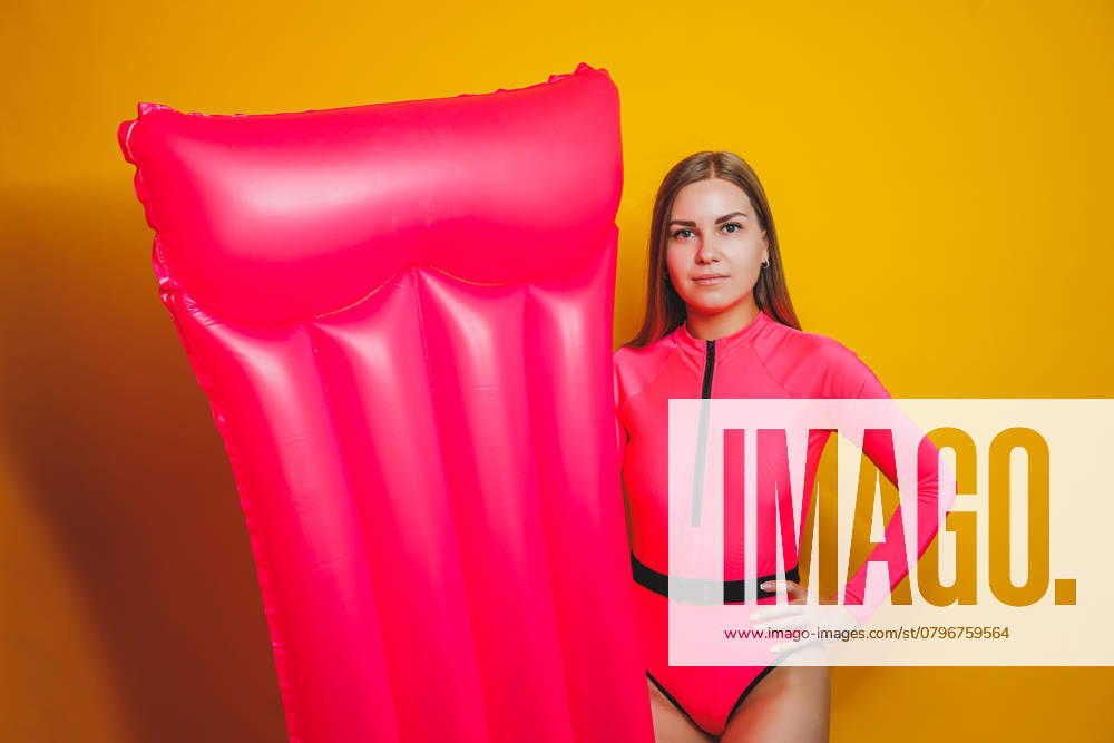 Young slender woman in a pink swimsuit on a yellow background. Girl with an inflatable mattress for swimming in the pool. Summer vacation., model released, , 48571398.jpg, woman, female, bikini, model, happy, girl, holiday, white, people, swimsuit, summer, person, sunglasses, adult, caucasian, beauty, cheerful, summertime, studio, leisure, beach, fashion, vacation, beautiful, water, yellow, pink, relax, travel, sexy, young, pool, posing, stylish, swim, body, float, red, blue, attractive, bed, inflatable, mattress, swimming, sunbathing, slim, lady, rubber, tropical, suntan RECORD DATE NOT STATED