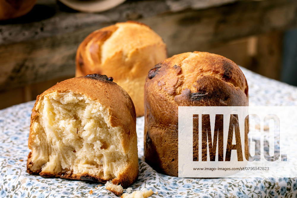 Hausgemachtes traditionelles italienisches Brioche-Weizenbrot ganz und halb Homemade traditional italian brioche wheat bread with cheese inside, whole and half. Standing on kitchen table with rustic floral tablecloth. Close up