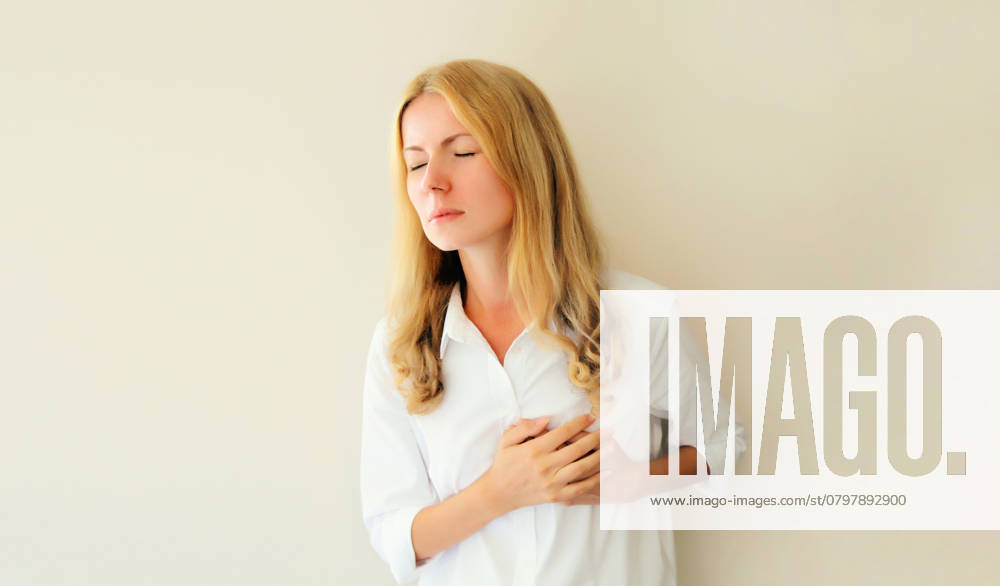 Frau, die sich die Hände auf die Brust legt und unter Herzschmerzen leidet, fühlt sich schlecht mit akuten Schmerzen Young woman grabbing put hands on her chest suffering from heart pain, feeling bad with acute pain in office ,model released, Symbolfoto