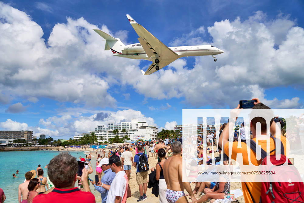 Eine Gulfstream G650 im Landeanflug über den Maho Beach in Sint Maarten. Touristen beobachten das spektakuläre Ereignis, während das Flugzeug zum Princess Juliana International Airport ansetzt