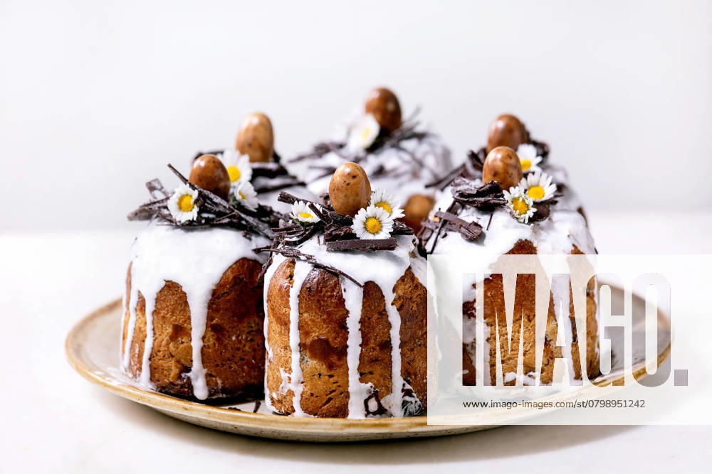 Hausgemachter traditioneller orthodoxer Osterkuchen traditioneller Kulich Homemade traditionla Easter kulich cake with chocolate nests and eggs on ceramic plate over white texture background. Traditional ortodox easter Russian Ukrainian bake