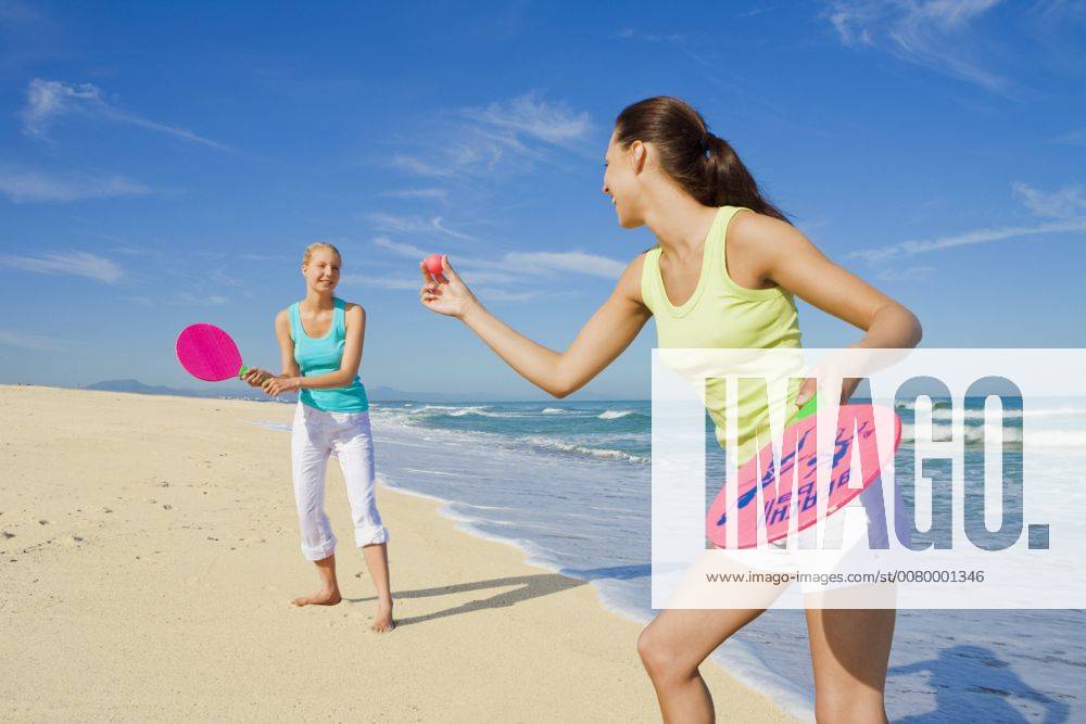 Two young women having fun at the beach and playing beach ball together A5