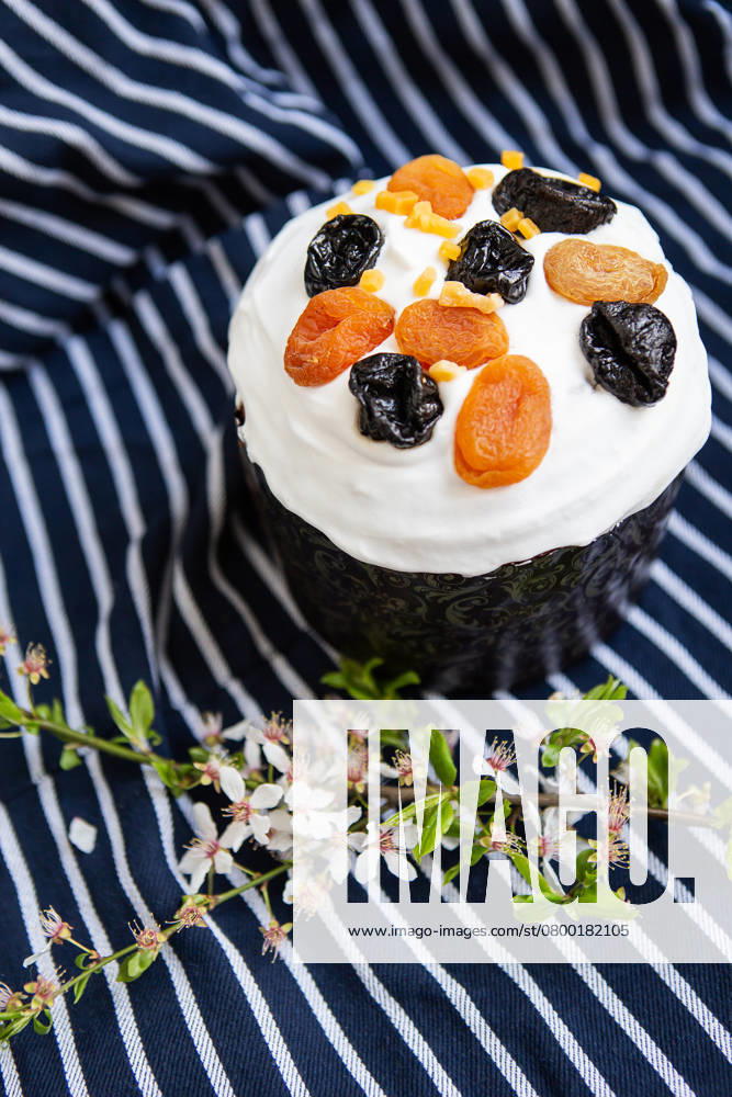 Easter cake, decorated with dried apricots and prunes, stands on a striped blue apron, a flowering branch. Easter religious holiday concept , 49605914.jpg, Easter, cake, holiday, tradition, traditional, decoration, multi colored, eggs, spring, celebration, watercolor, religion, food, icing, green, flower, prune, dried apricots, cream, sweet, festive, delicious, white, baked, pastry shops products, symbol, culture, table, sugar, dessert, bread, christianity, close up, decorative, bakery, glazed, biscuit, blue, colorful, season, pink, homemade, nobody, wooden, flora, plant, sand cover, brown, apron RECORD DATE NOT STATED