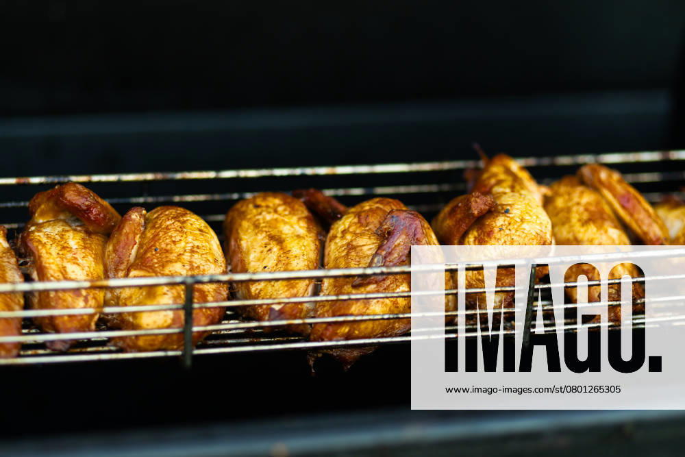 Juicy grilled chickens cooking on a metal rack, highlighting the vibrant street food scene at an outdoor fair. Model Released Ptashkimenko_ID26235_756766_005