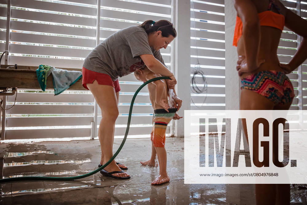 IMAGO Creative, Sommer, Sommertage im Garten Mother rinsing sand off child after summer beach day Edisto Island, South Carolina, United States CR_WEKW250221-1658542-01 ,model released, Symbolfoto