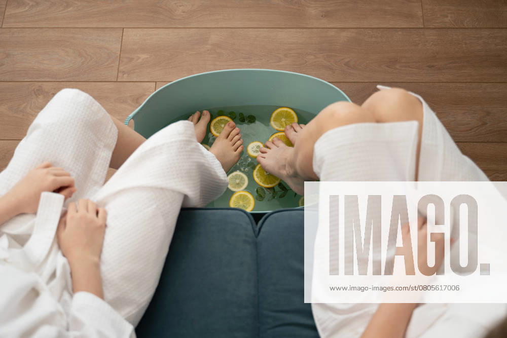 PR_ID26632_10596_Room.jpg, MR_ID26632_19749_DariaGolubeva.jpg, MR_ID26632_19750_JuliaGolubeva.jpg Mother and daughter indulge in a soothing foot soak with citrus slices and herbs at home. Dressed in bathrobes, they share a peaceful, pampering moment together., Property released Model Released LiliyaSolopova_ID26632_768664_014