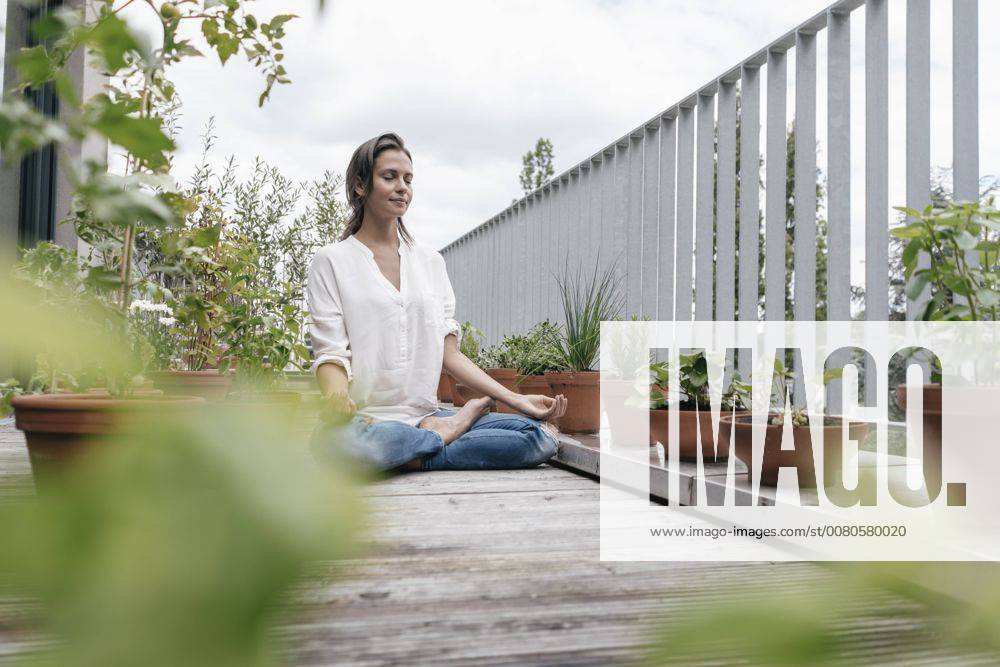 Woman sitting on balcony practicing yoga model released Symbolfoto property released JOSF01578
