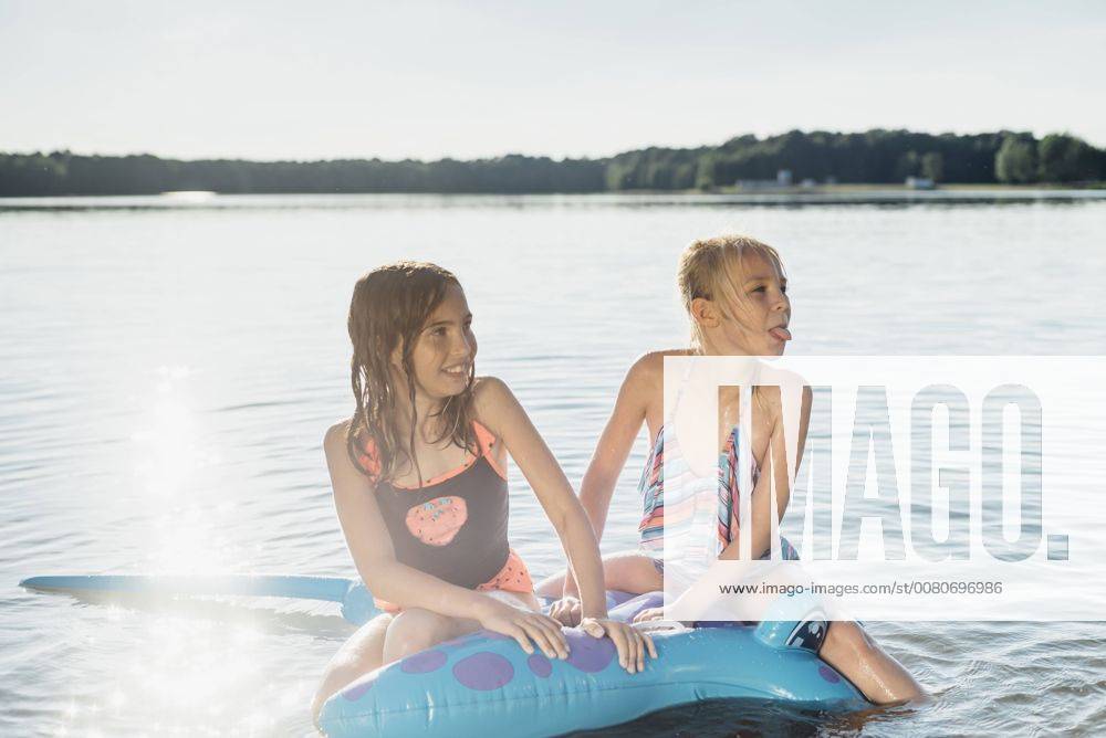 Two girls sitting on swim toy in the water model released Symbolfoto MJF02188