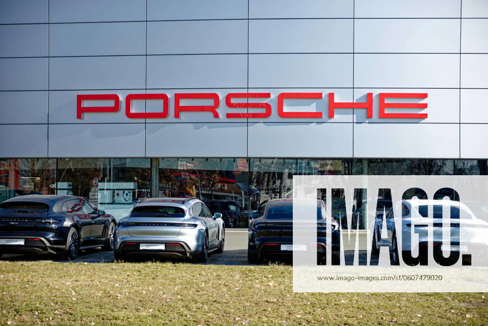 Schriftzug der Automarke Porsche an der Fassade des Porschezentrums in Nürnberg mit davor geparkten Fahrzeugen