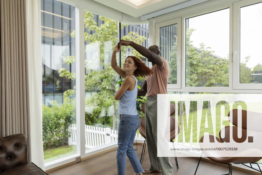 Happy multiracial couple dancing in a bright living room model released, Symbolfoto property released, ALZF00997
