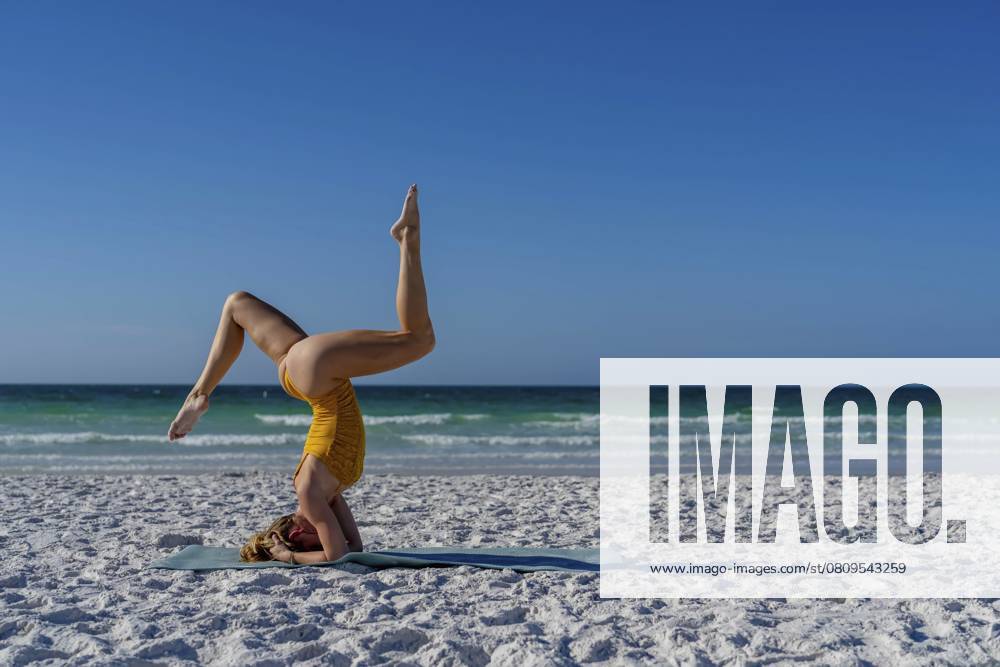Eine ruhige und malerische Szene mit einem schönen blonden Modell übt Yoga am Strand in den frühen Morgenstunden, Sarasota, Vereinigte Staaten von Amerika, Nordamerika A serene and picturesque scene with a beautiful blonde model practicing yoga on the beach in the early morning, Sarasota, United States of America