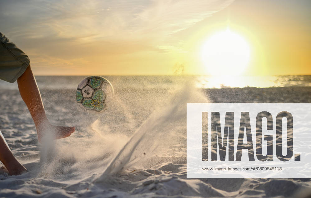 Boy kicking ball on beach towards beautiful sunset on the horizon Adelaide, South Australia, Australia R_PAOL250404-1698006-01 ,model released, Symbolfoto