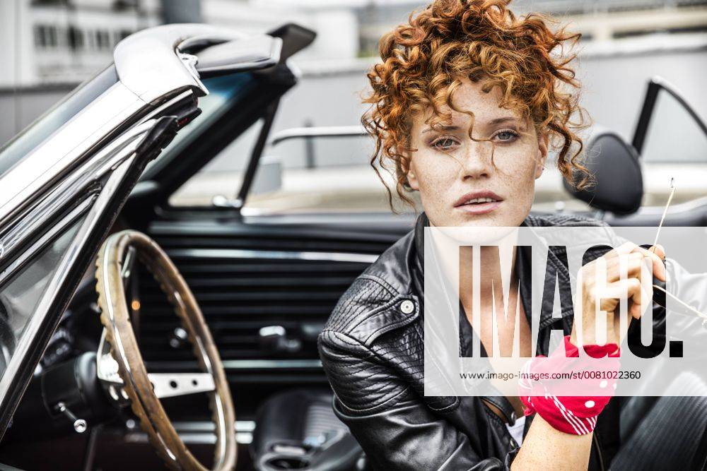 Portrait of confident redheaded woman in sports car model released Symbolfoto FMKF04497