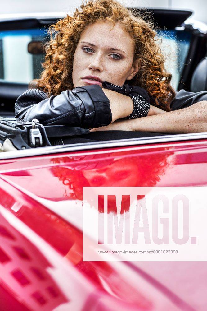 Portrait of confident redheaded woman in sports car model released Symbolfoto FMKF04519