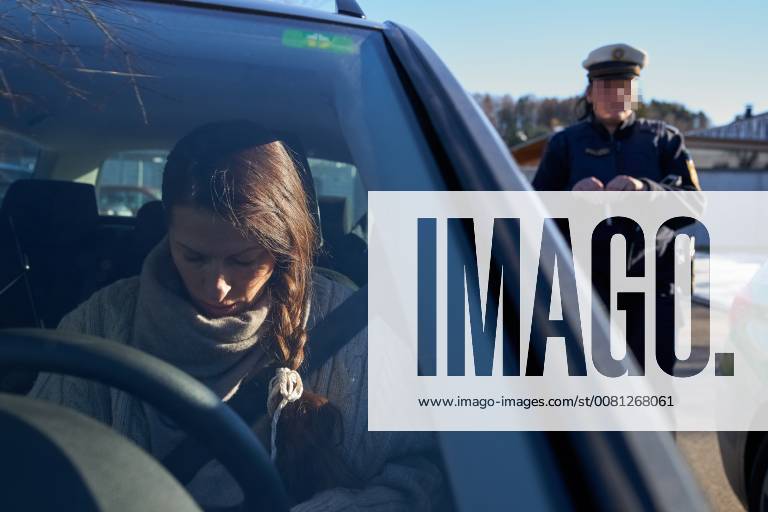 Junge Frau mit Handy am Steuer eines PKW (gestellte Szene) bei einer Polizeikontrolle mit Alkoholkontrolle, Promille, Polizistin, in Marktoberdorf, Bayern, Deutschland am 07.12.2017 FRAU AM STEUER MODEL RELEASED