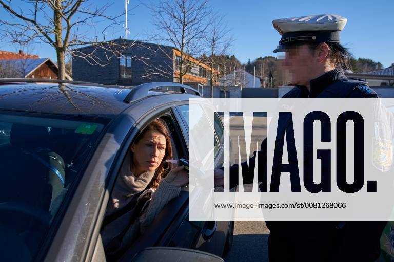 Junge Frau mit Handy am Steuer eines PKW (gestellte Szene) bei einer Polizeikontrolle mit Alkoholkontrolle, Promille, Polizistin, in Marktoberdorf, Bayern, Deutschland am 07.12.2017 FRAU AM STEUER MODEL RELEASED