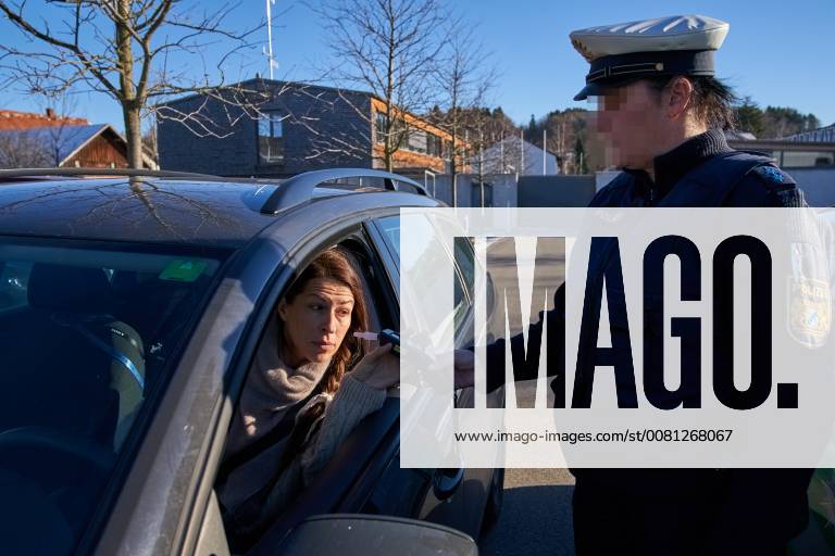 Junge Frau mit Handy am Steuer eines PKW (gestellte Szene) bei einer Polizeikontrolle mit Alkoholkontrolle, Promille, Polizistin, in Marktoberdorf, Bayern, Deutschland am 07.12.2017 FRAU AM STEUER MODEL RELEASED
