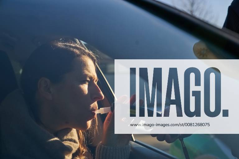 Junge Frau mit Handy am Steuer eines PKW (gestellte Szene) bei einer Polizeikontrolle mit Alkoholkontrolle, Promille, Polizistin, in Marktoberdorf, Bayern, Deutschland am 07.12.2017 FRAU AM STEUER MODEL RELEASED