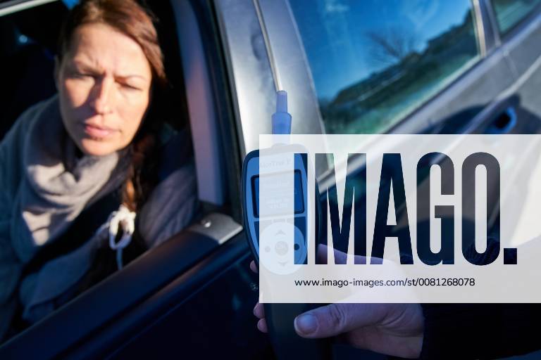 Junge Frau mit Handy am Steuer eines PKW (gestellte Szene) bei einer Polizeikontrolle mit Alkoholkontrolle, Promille, Polizistin, in Marktoberdorf, Bayern, Deutschland am 07.12.2017 FRAU AM STEUER MODEL RELEASED