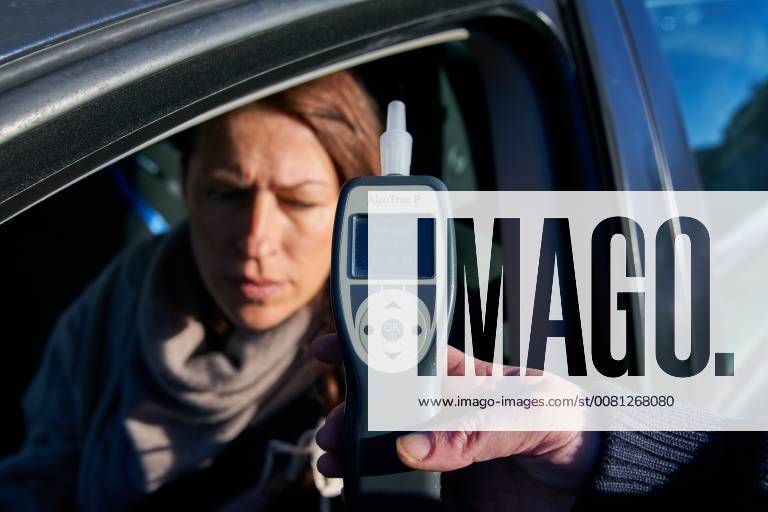 Junge Frau mit Handy am Steuer eines PKW (gestellte Szene) bei einer Polizeikontrolle mit Alkoholkontrolle, Promille, Polizistin, in Marktoberdorf, Bayern, Deutschland am 07.12.2017 FRAU AM STEUER MODEL RELEASED