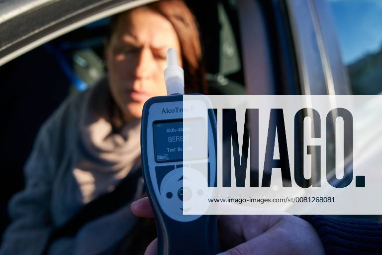 Junge Frau mit Handy am Steuer eines PKW (gestellte Szene) bei einer Polizeikontrolle mit Alkoholkontrolle, Promille, Polizistin, in Marktoberdorf, Bayern, Deutschland am 07.12.2017 FRAU AM STEUER MODEL RELEASED
