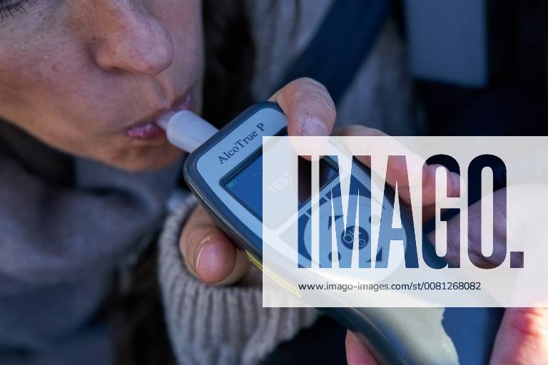 Junge Frau mit Handy am Steuer eines PKW (gestellte Szene) bei einer Polizeikontrolle mit Alkoholkontrolle, Promille, Polizistin, in Marktoberdorf, Bayern, Deutschland am 07.12.2017 FRAU AM STEUER MODEL RELEASED