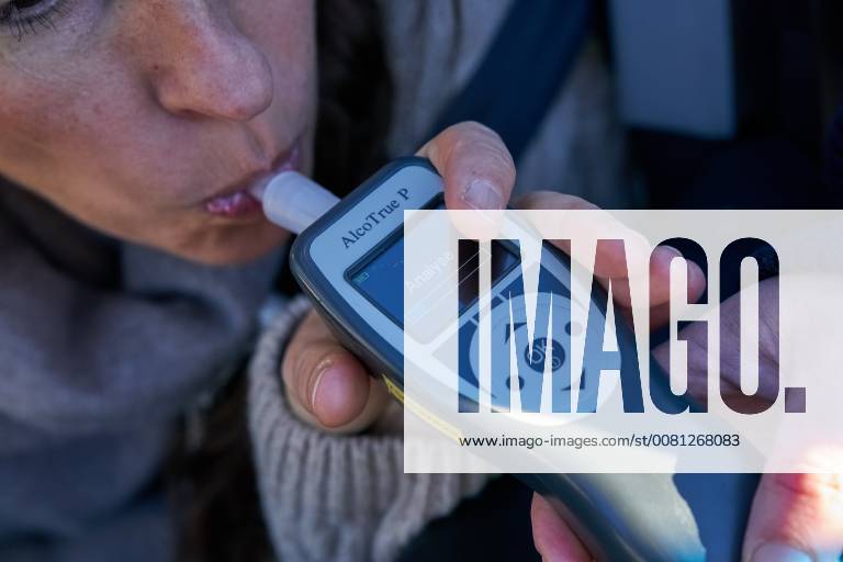 Junge Frau mit Handy am Steuer eines PKW (gestellte Szene) bei einer Polizeikontrolle mit Alkoholkontrolle, Promille, Polizistin, in Marktoberdorf, Bayern, Deutschland am 07.12.2017 FRAU AM STEUER MODEL RELEASED