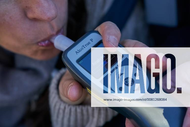 Junge Frau mit Handy am Steuer eines PKW (gestellte Szene) bei einer Polizeikontrolle mit Alkoholkontrolle, Promille, Polizistin, in Marktoberdorf, Bayern, Deutschland am 07.12.2017 FRAU AM STEUER MODEL RELEASED