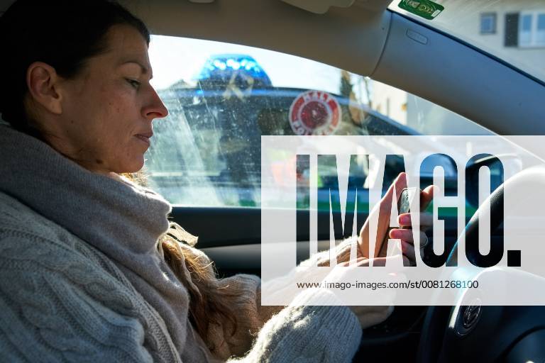 Junge Frau mit Handy am Steuer eines PKW (gestellte Szene) bei einer Polizeikontrolle in Marktoberdorf, Bayern, Deutschland am 07.12.2017 FRAU AM STEUER MODEL RELEASED