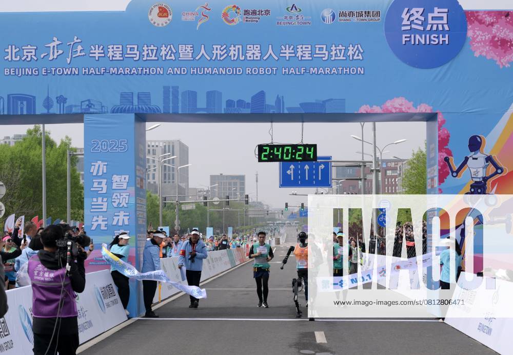 China, Roboter nehmen am Peking E Town Halbmarathon teil (250419) -- BEIJING, April 19, 2025 -- Robotic participant Tiangong Ultra (C) crosses with the finishing line as engineers run alongside during the Beijing E-Town half-marathon and humanoid robots half-marathon in the Beijing Economic-Technological Development Area in southeast Beijing, China, April 19, 2025. ) (SP)CHINA-BEIJING-E-TOWN HALF MARATHON AND HUMANOID ROBOTS HALF MARATHON (CN) LixHe