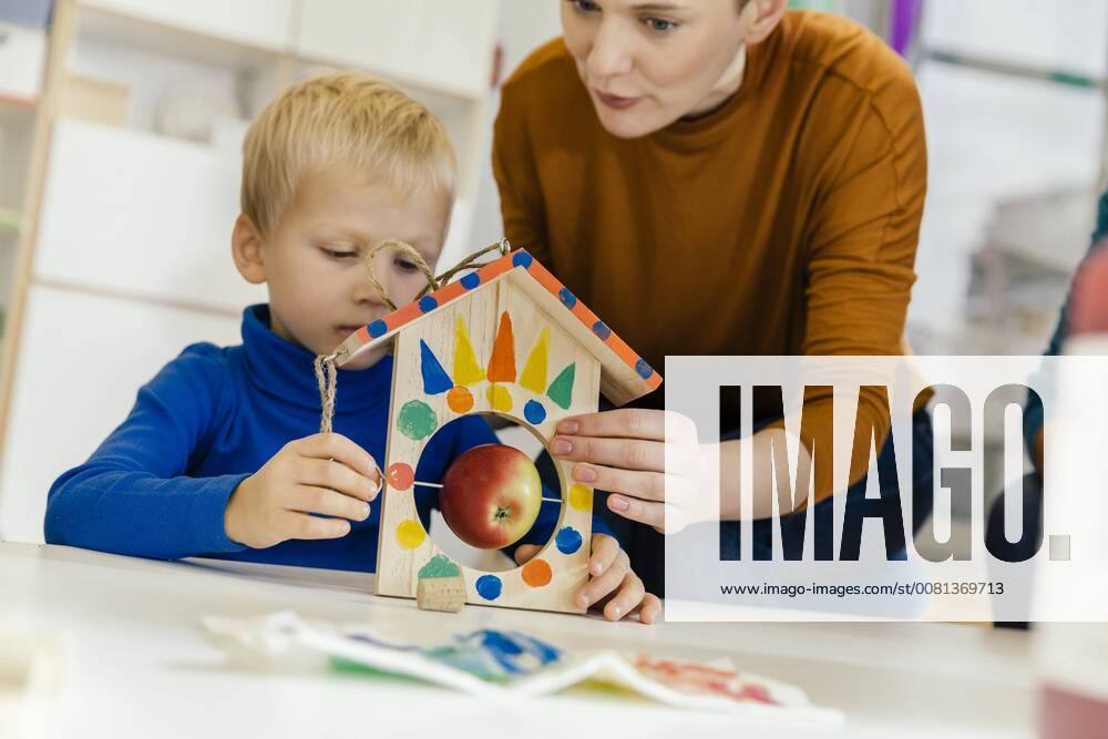 Child and pre-school teacher building a bird table in kindergarten model released Symbolfoto property released MFF04131