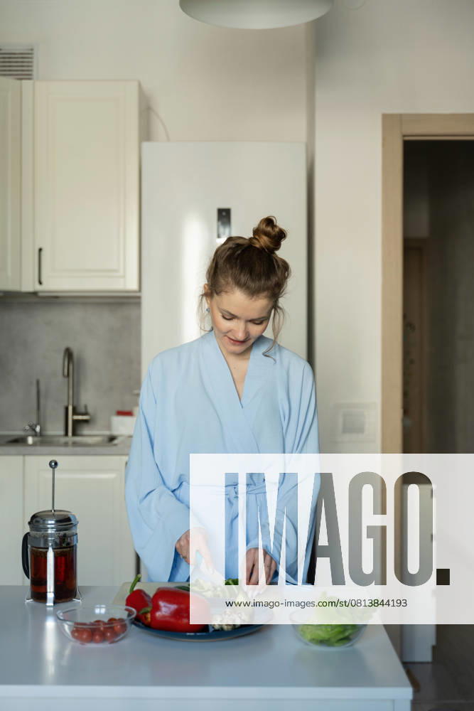 MR_ID27929_20617_TatyanaRangulova.jpg, PR_ID27929_10891_Cat.jpg, PR_ID27929_10892_Room.jpg A woman in a light blue robe prepares a healthy breakfast in her kitchen, surrounded by fresh vegetables and a French press coffee maker, embodying a cozy home atmosphere., Property released Model Released LiliyaSolopova_ID27929_802055_001
