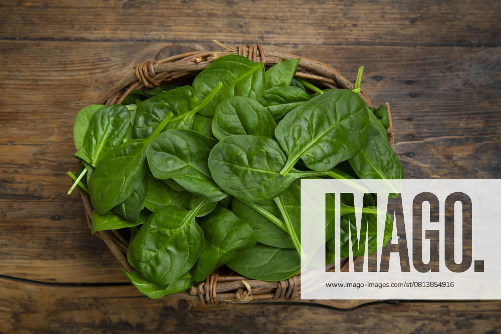 Fresh baby spinach in a willow basket on a wooden background, LVF09447