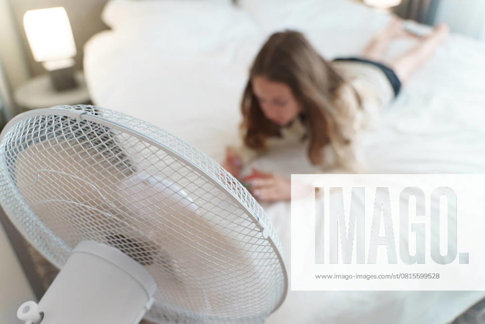 Ein Teenager liegt mit dem Telefon vor einem Ventilator. Teenager lies with the phone in front of cooling fan. (License=RF) ,model released, Symbolfoto