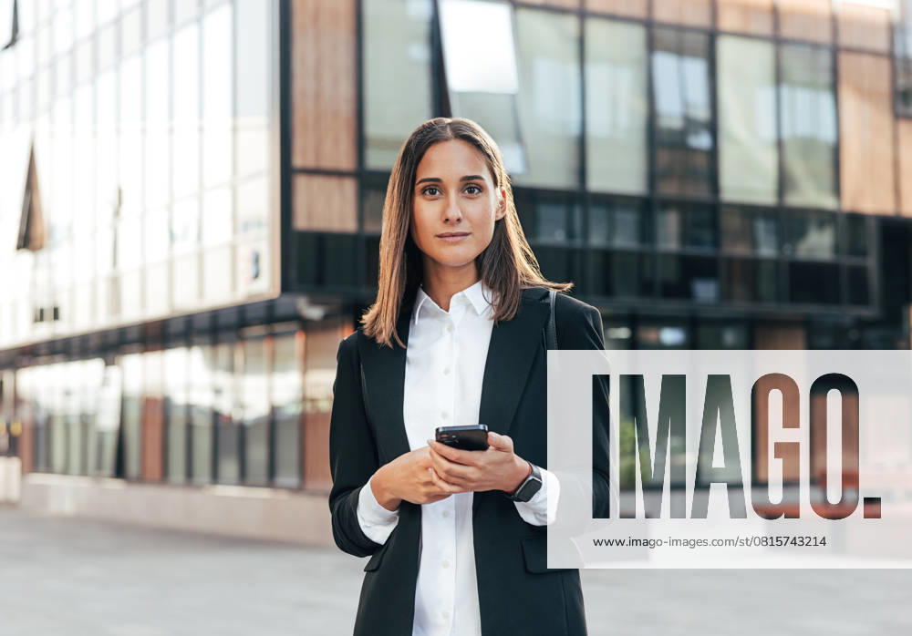 Portrait of a young woman in formal wear standing outside against an office building Portrait of a young woman in formal wear standing outside against an office building