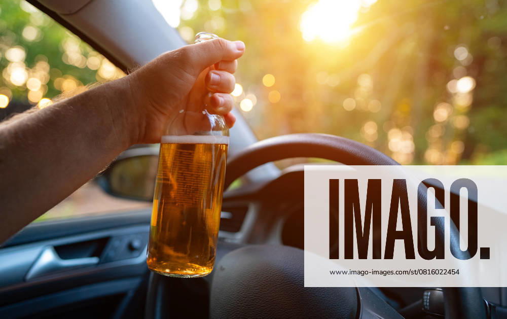 Mann mit einer Bierflasche im Auto. Konzept der Trunkenheit am Steuer. Man with a bottle of beer in the car. Drunk driving concept. (License=RF)