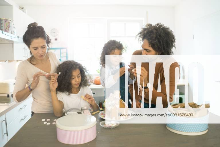 Family pasting gingerbread house in kitchen for Christmas with sweets model released Symbolfoto property released MOEF00378