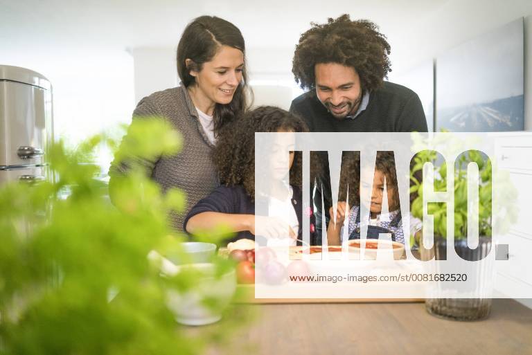 IMAGO Creative: Digitale Welt, Verzicht auf Technologie Family baking pizza in kitchen, daughter spreading tomato sauce model released Symbolfoto property released MOEF00300