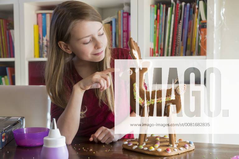 Smiling girl with homemade gingerbread reindeer at home model released Symbolfoto SARF03448