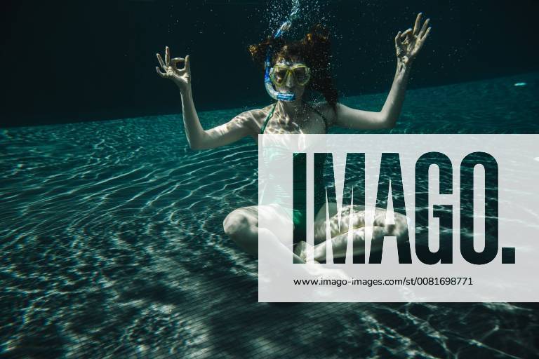 Woman with diving goggles and snorkel sitting in yoga pose underwater in a swimming pool model released Symbolfoto MFF04253