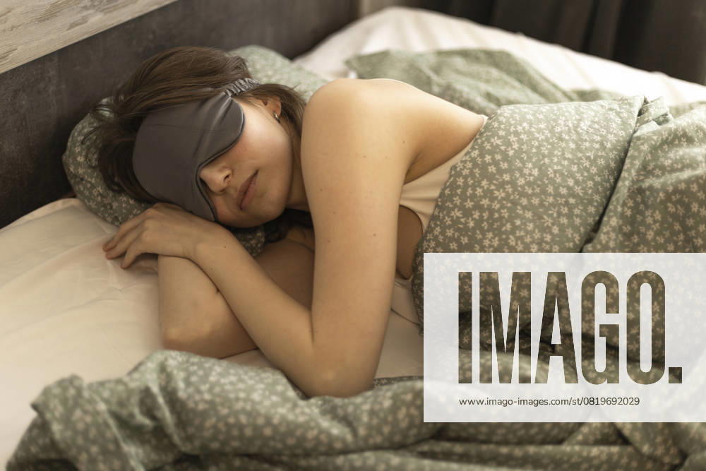 Woman sleeping on her side in bed wearing a silk sleep mask R_DCGM250515-1732436-01 ,model released, Symbolfoto