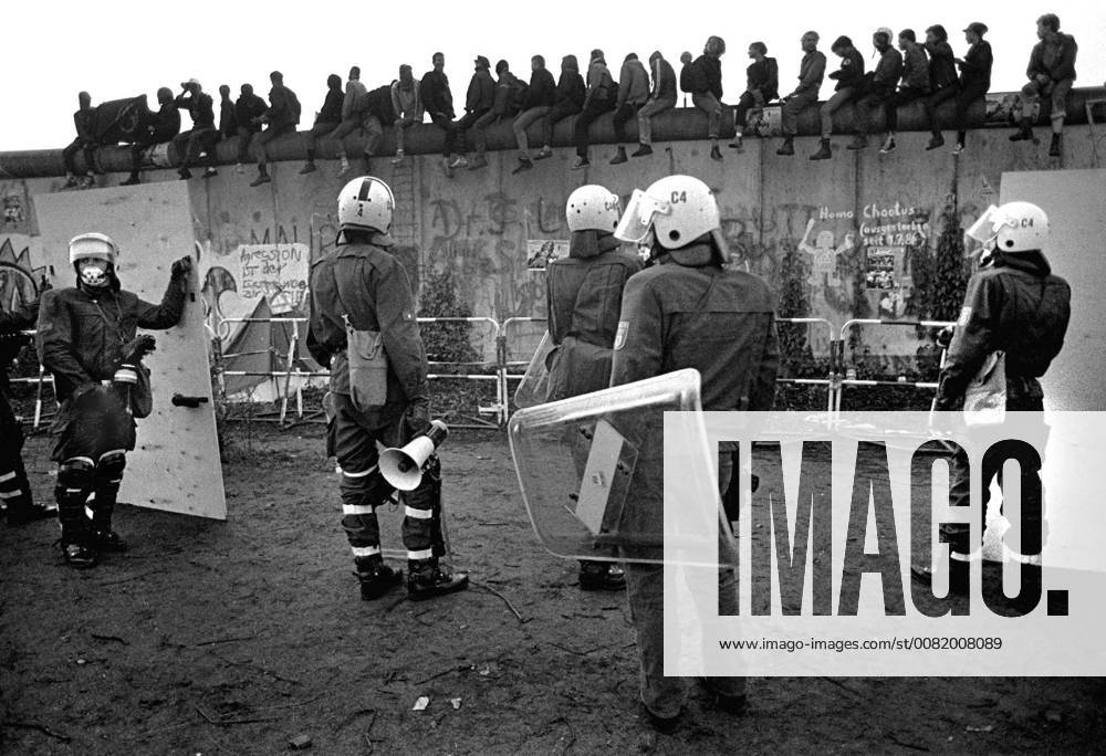 Berlin 1. Juli 1988 -Besetzer fluechten nach Ostberlin. Polizei rauemt in den fruehen Morgenstunden das von Autonomen besetzte Lenne-Dreieck am Potsdamer Platz. Im Rahmen eines Gebietsaustausches mit der DDR wurde das Gebiet am 1.Juli 88 an Westberlin uebertragen. Die Besetzer fluechteten ueber die Berliner Mauer nach Ostberlin, wo sie von DDR-Grenzsoldaten freundlich empfangen wurden und ueber verschiedene Grenzuebergaenge wieder nach Westberlin gebracht wurden. im Bild: Besetzer sitzen auf der Mauer